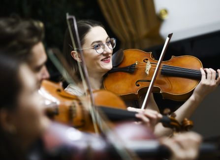A photograph. A string concert in Villa Decius. Three women play the violin.